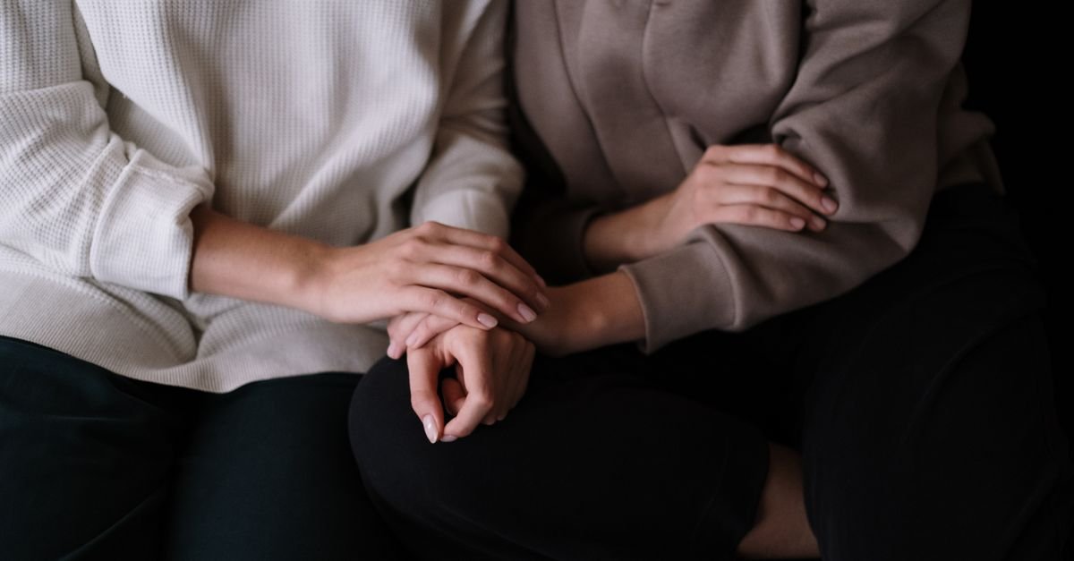 Mãos de duas pessoas em gesto de apoio e acolhimento