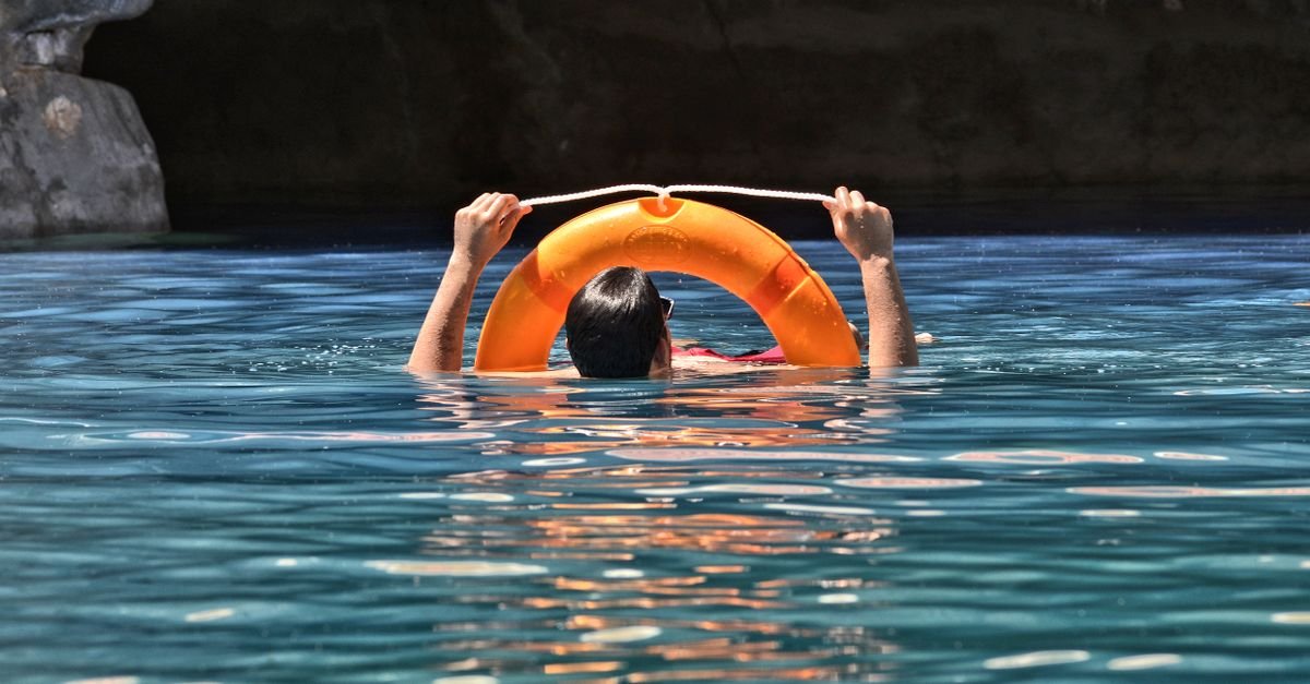 Pessoa segura boia salva-vidas laranja em piscina