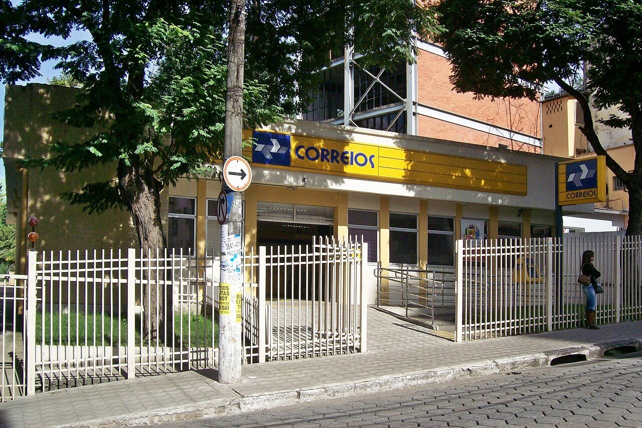 Fachada amarela de uma agencia dos Correios com o logotipo da empresa acima da entrada