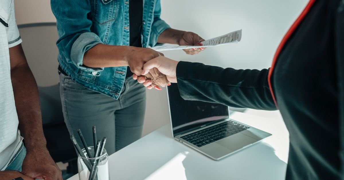 Candidata entrega currículo e cumprimenta recrutadora em atendimento de emprego