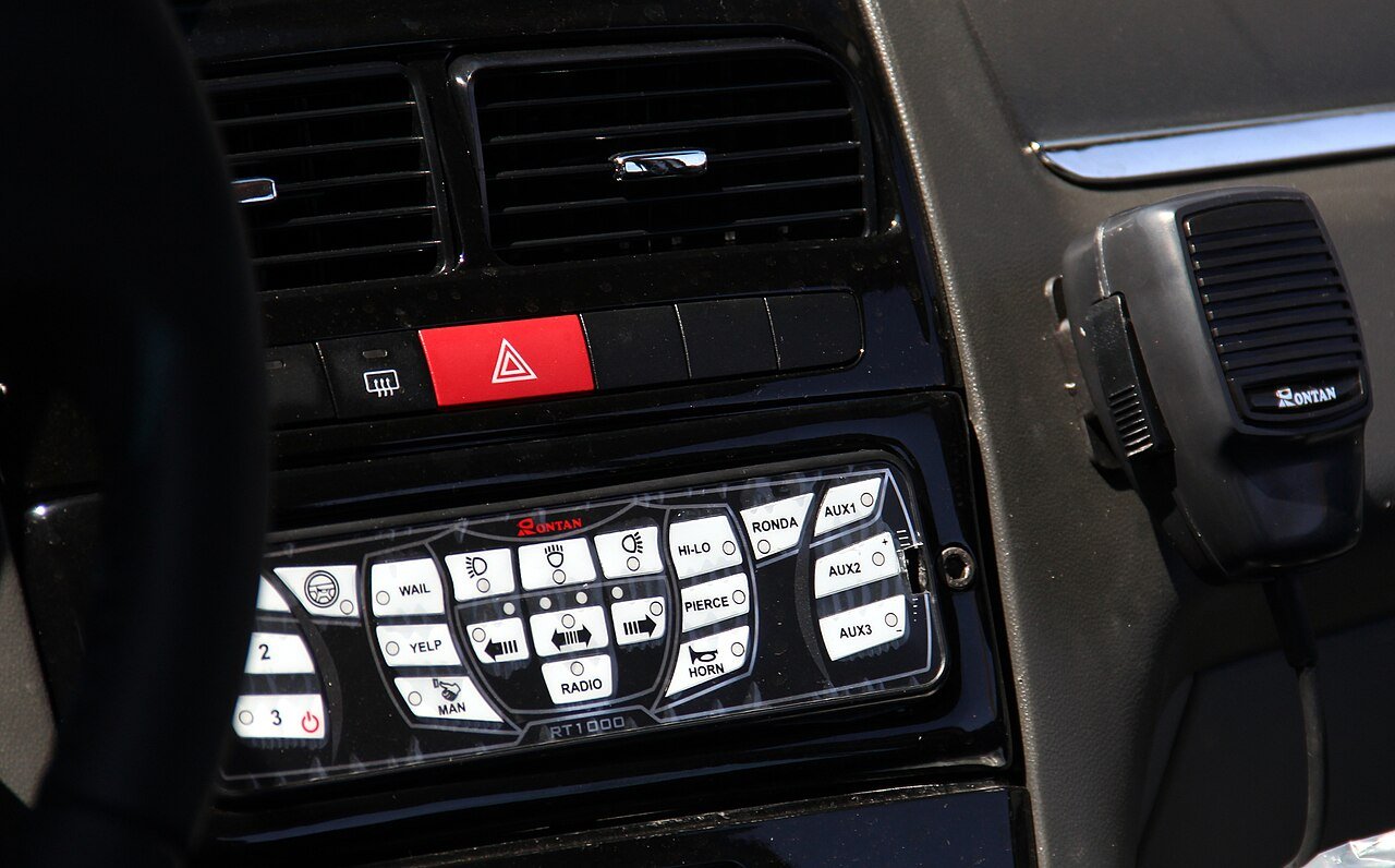 Painel interno de viatura policial com controle de sirene e microfone de rádio