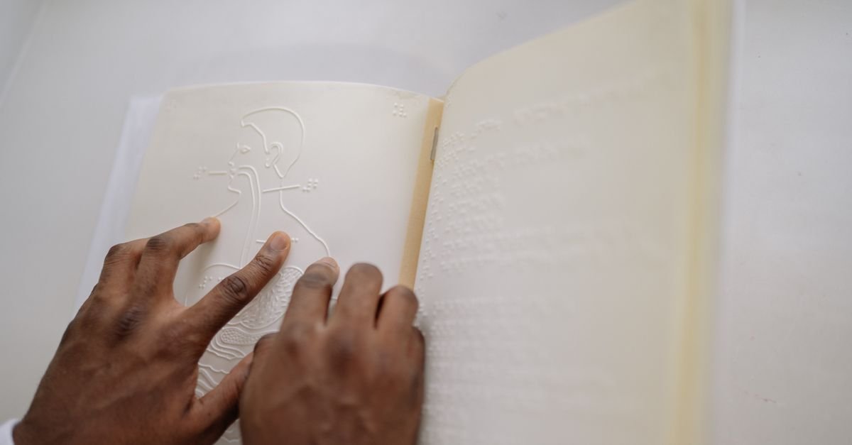 Mãos lendo as páginas em relevo de um livro em braile