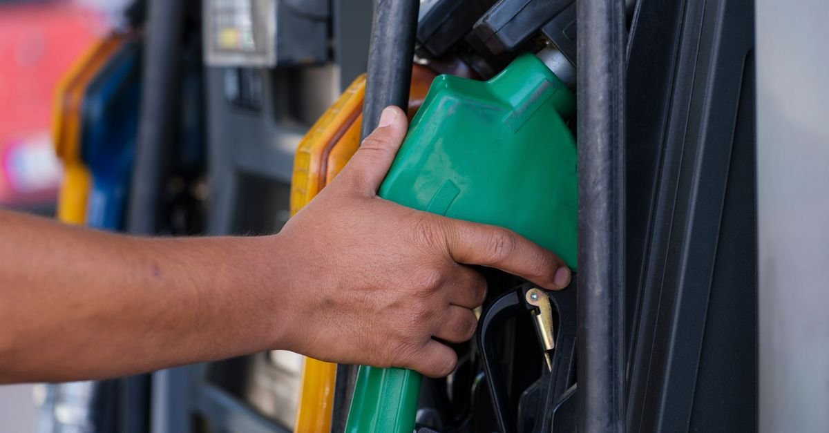 Mão segura bico verde de abastecimento em bomba de posto de combustível
