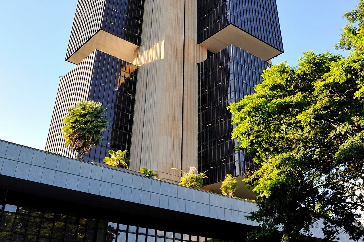 Edifício sede do Banco Central do Brasil, em Brasília, visto de baixo com vegetação em primeiro plano