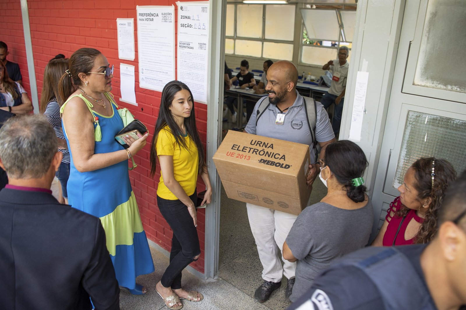 Mesário carrega caixa de urna eletrônica na entrada de uma escola no segundo turno de 2022, em foto de arquivo