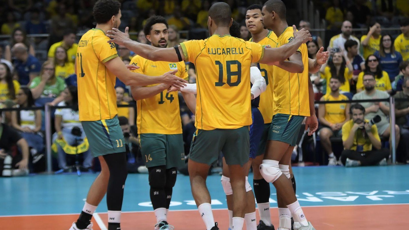 Jogadores da seleção brasileira masculina de vôlei, de camisa amarela, comemoram ponto reunidos na quadra do Maracanãzinho