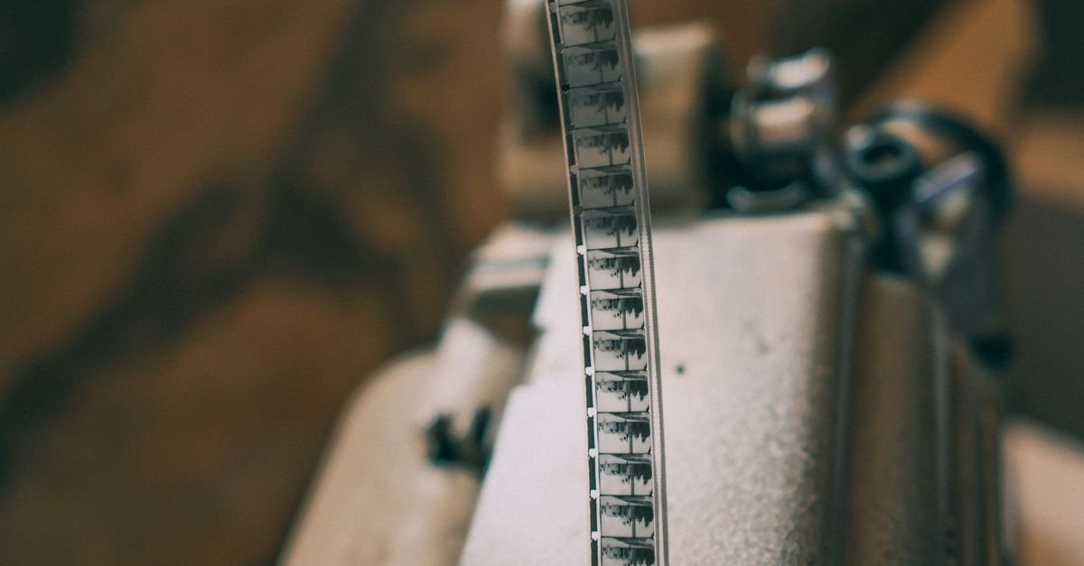 Película de filme 35 mm passando por um projetor cinematográfico antigo
