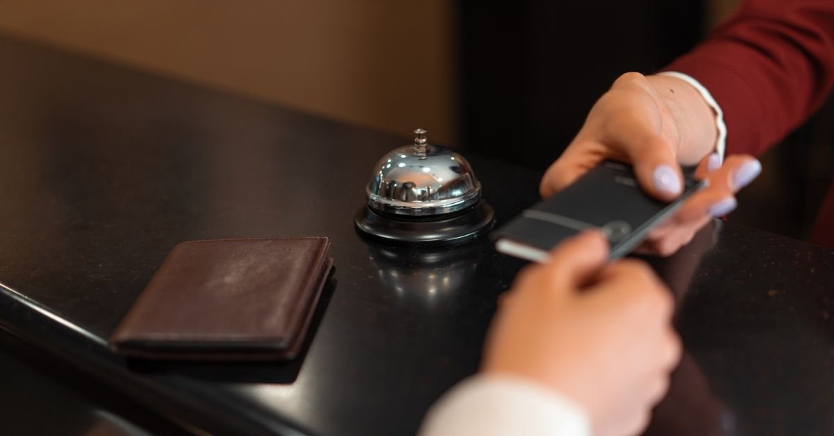 Balcão de recepção de hotel com sino, carteira e celular durante atendimento
