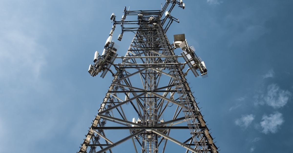 Torre de telecomunicações vista de baixo, com antenas contra o céu azul