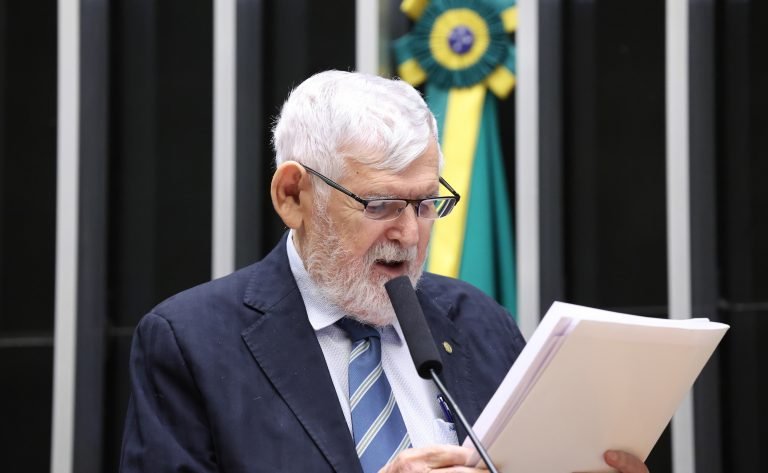 Deputado lê documento no microfone durante sessão no plenário da Câmara dos Deputados