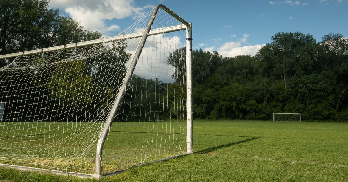 Trave com rede em campo de futebol gramado, sem público