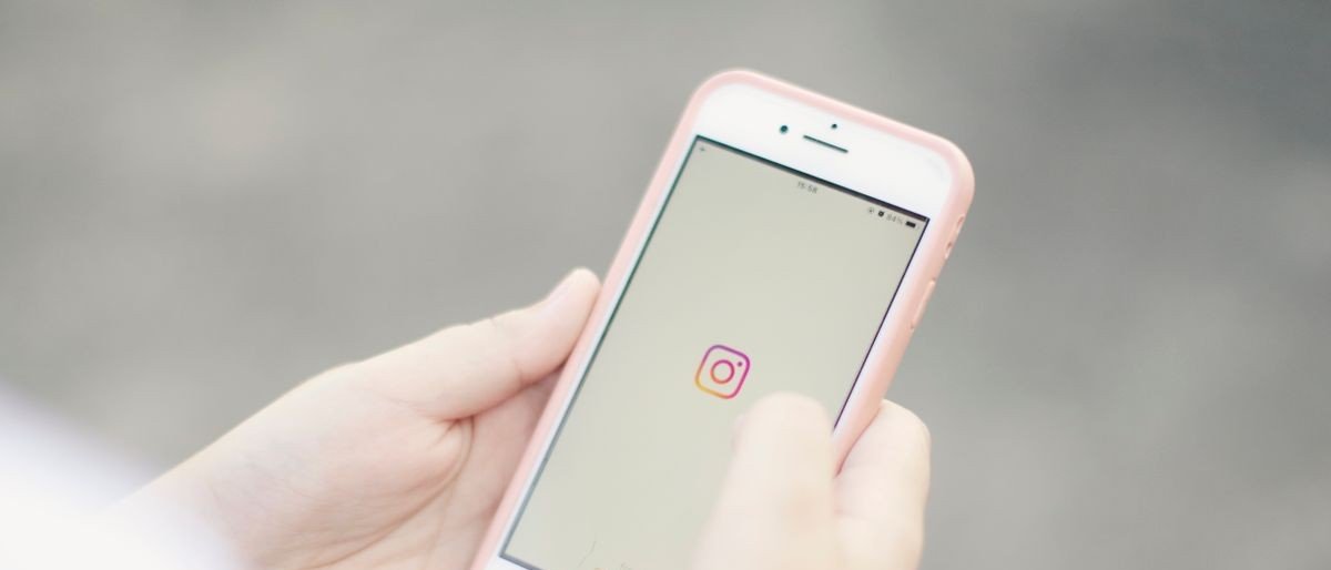 Mão segura celular com o aplicativo do Instagram aberto na tela