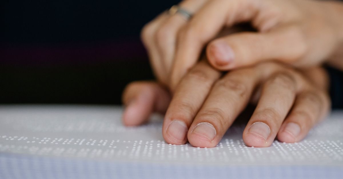 Mãos leem página em braille, símbolo de acessibilidade e tecnologia assistiva