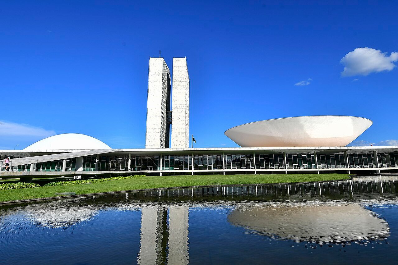 Fachada do Congresso Nacional em Brasília, com as duas torres e as cúpulas refletidas no espelho d'água