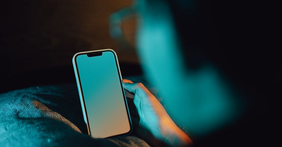 Pessoa segura celular com a tela acesa em ambiente escuro