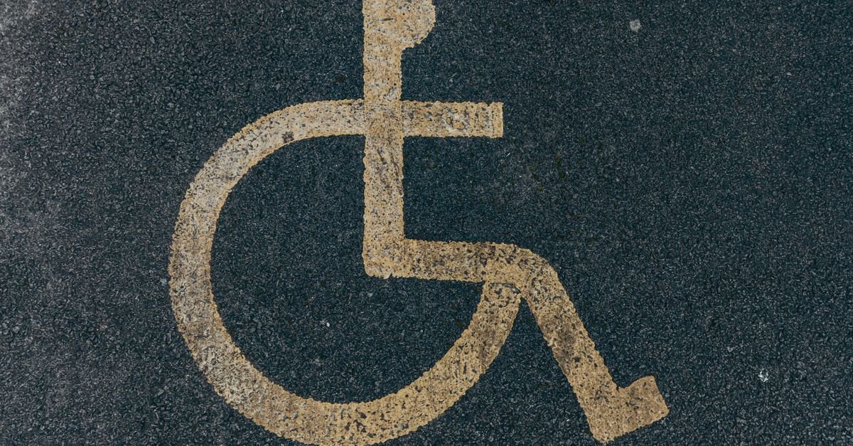 Símbolo internacional de acessibilidade pintado em amarelo sobre asfalto escuro