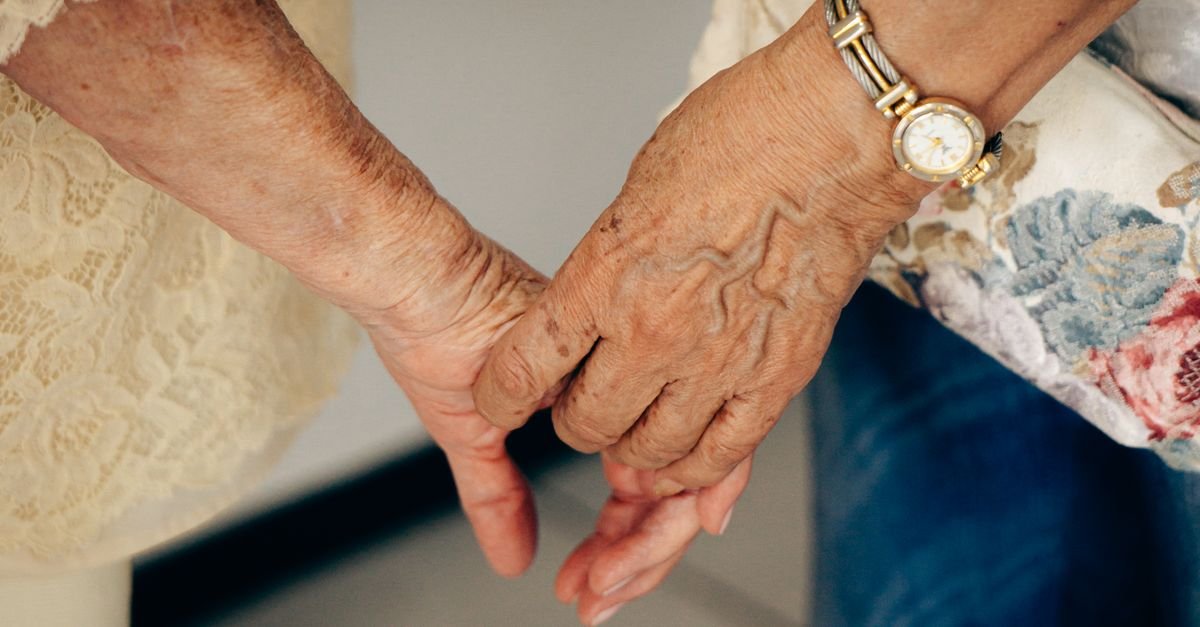 Mãos de duas mulheres idosas dadas em close