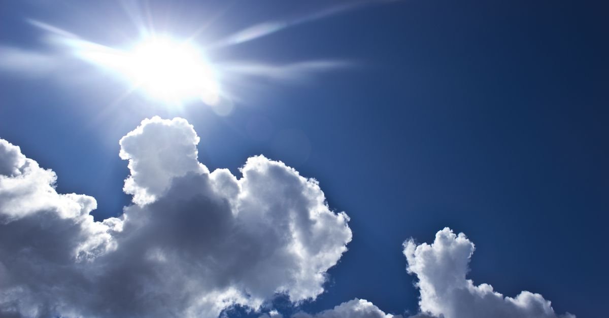 Sol forte em céu azul com nuvens brancas