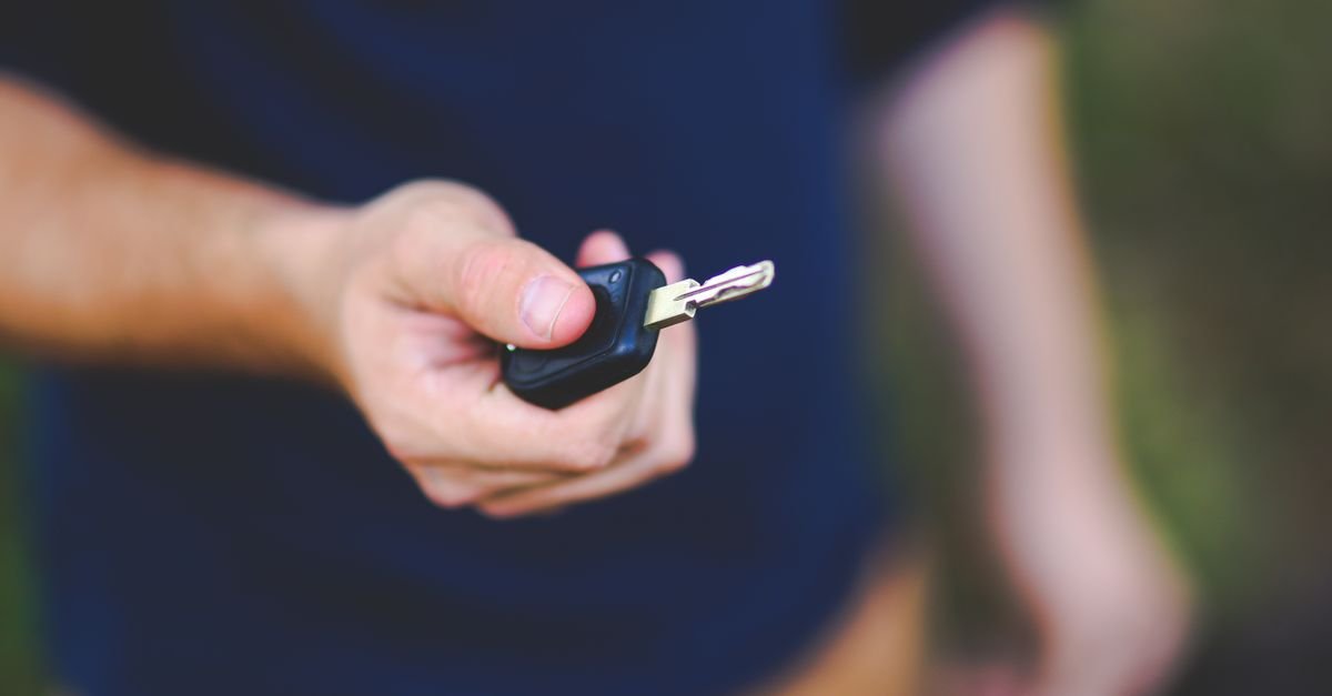 Mão estendida segurando uma chave de carro com controle remoto