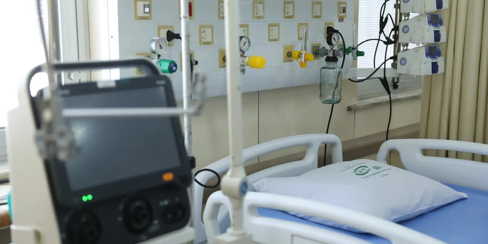Leito hospitalar com monitor, painel de gases medicinais e cama vazia