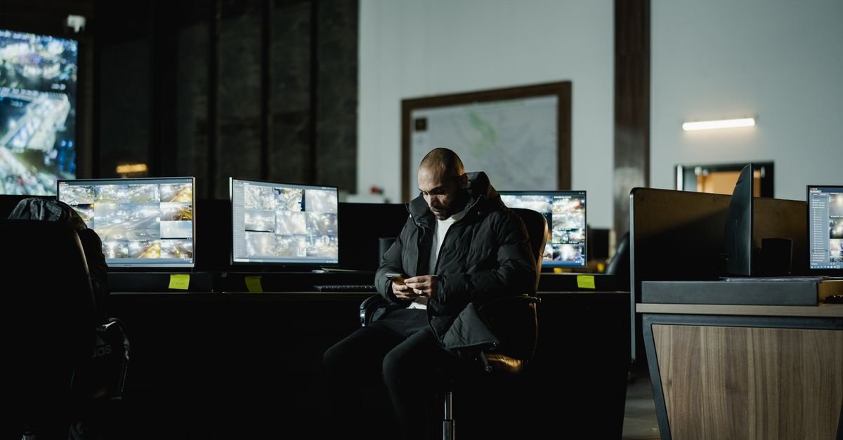 Sala de monitoramento com várias telas exibindo imagens de câmeras de vigilância