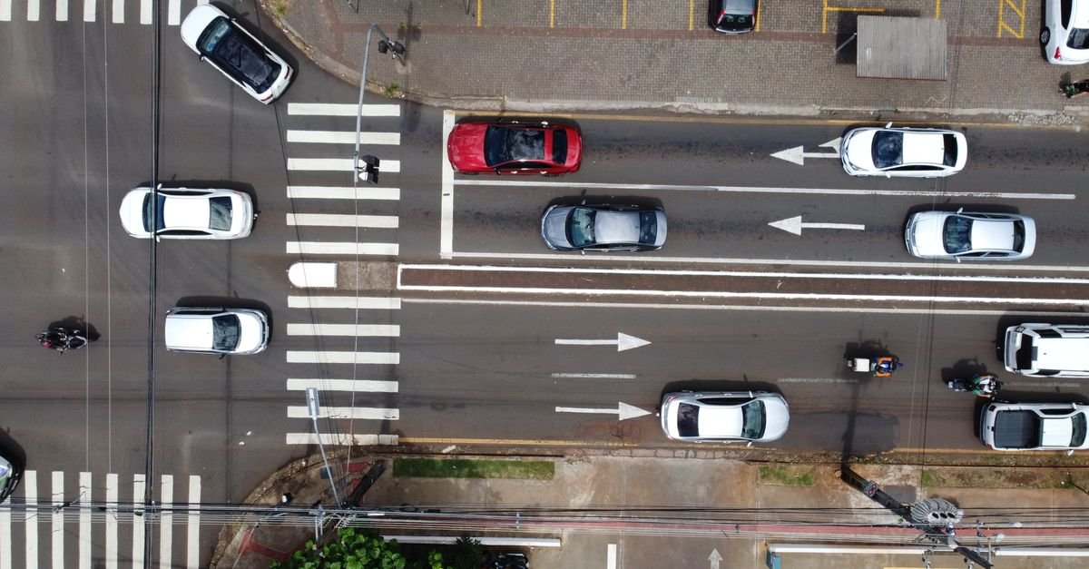 Vista aérea de avenida com faixa de pedestres e veículos em duas mãos