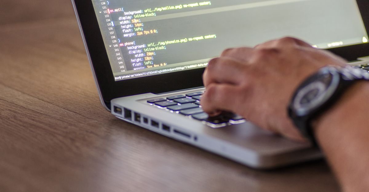 Mãos de profissional digitando código em laptop