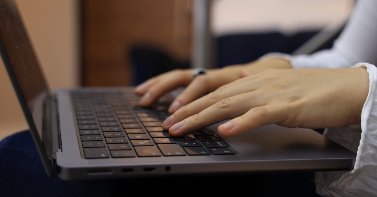 Mãos digitam em notebook durante estudo para o concurso da Receita Federal