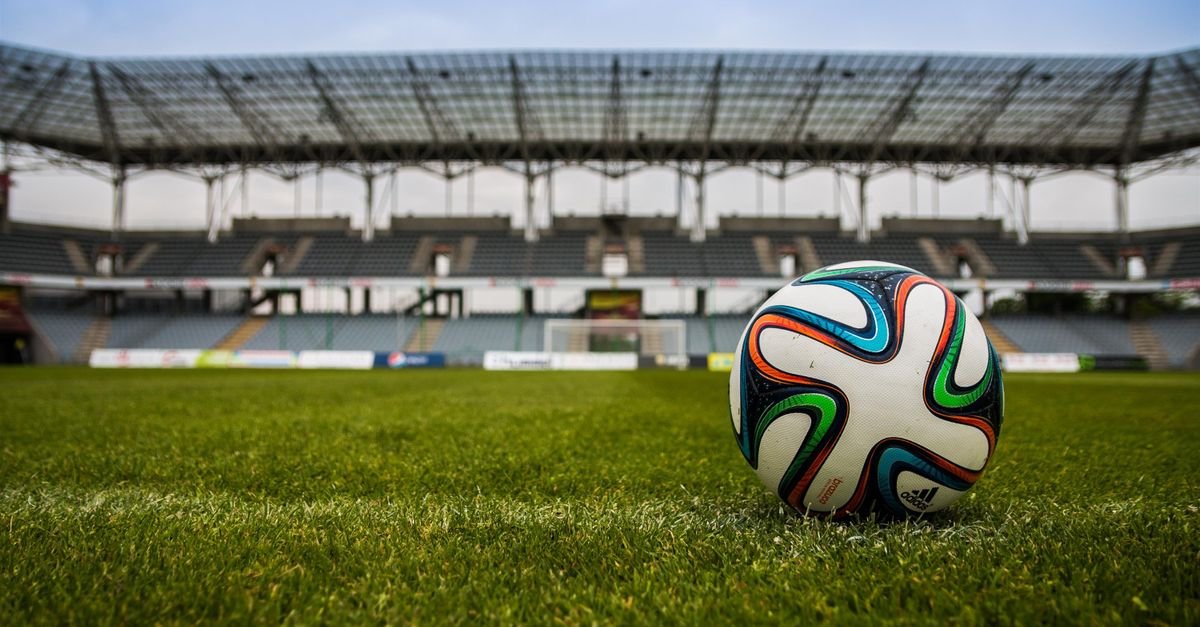 Bola de futebol em gramado de estádio vazio