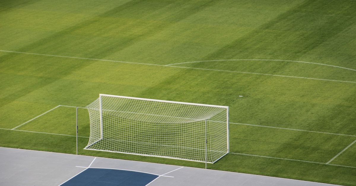 Gol de futebol com rede branca em campo de grama