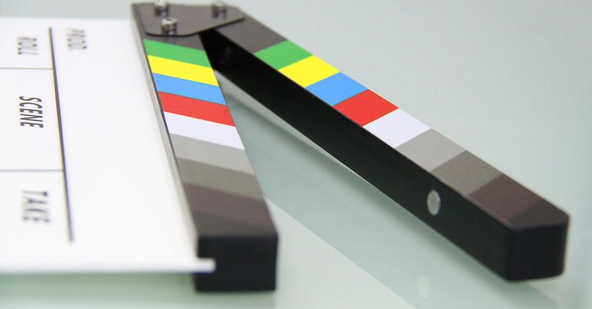 Claquete de cinema aberta sobre superfície clara, usada em gravações audiovisuais