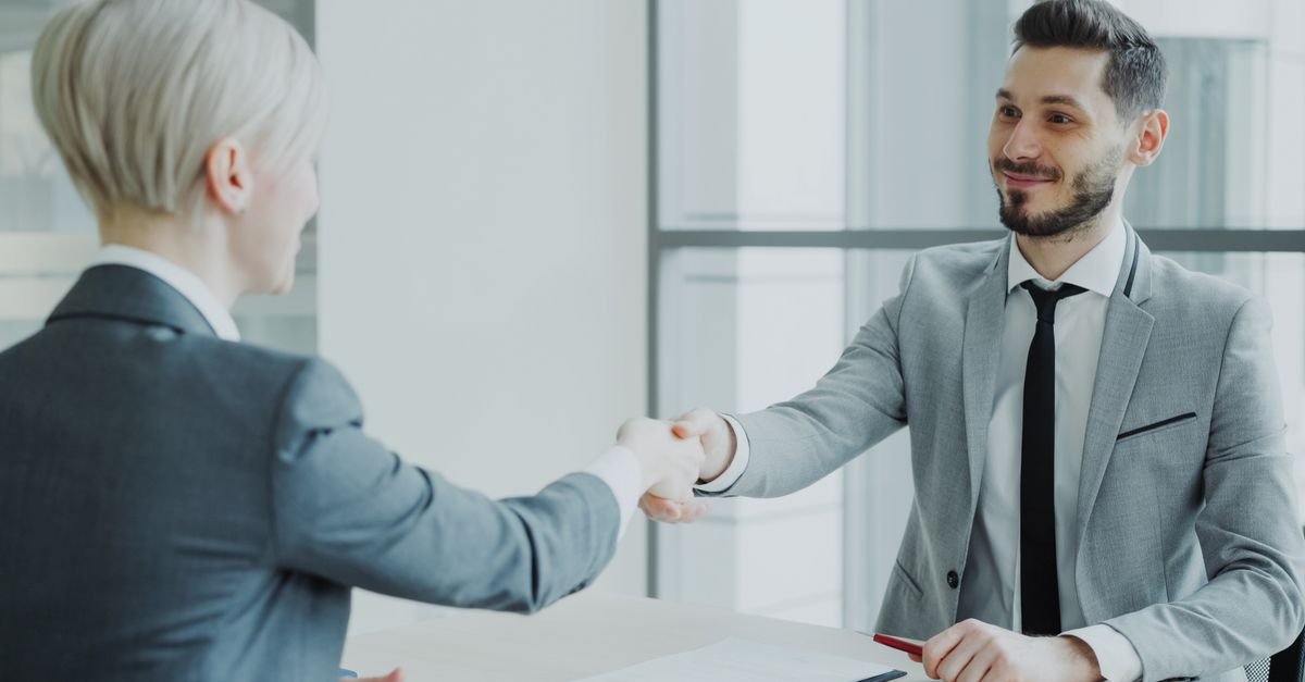Aperto de mãos entre duas pessoas em ambiente de escritório após entrevista de emprego