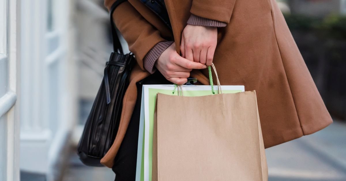Consumidora carrega sacolas de papel de compras na rua