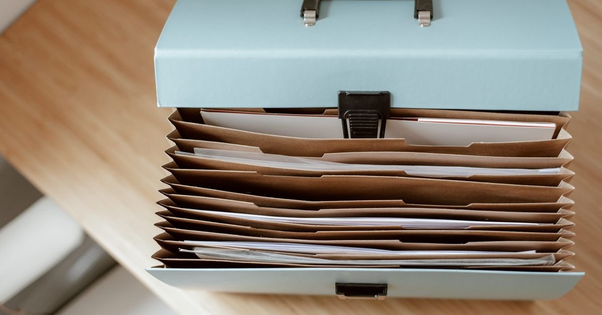 Maleta organizadora com pastas e documentos vista de cima sobre mesa de madeira