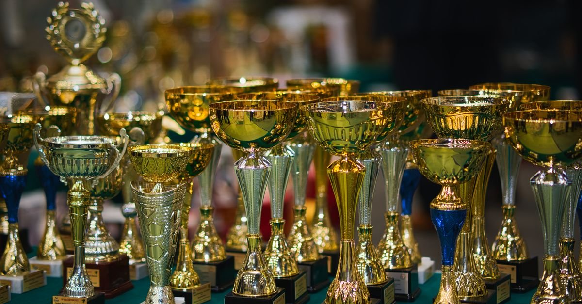 Array of golden trophies on a table, reflecting victory and achievement.