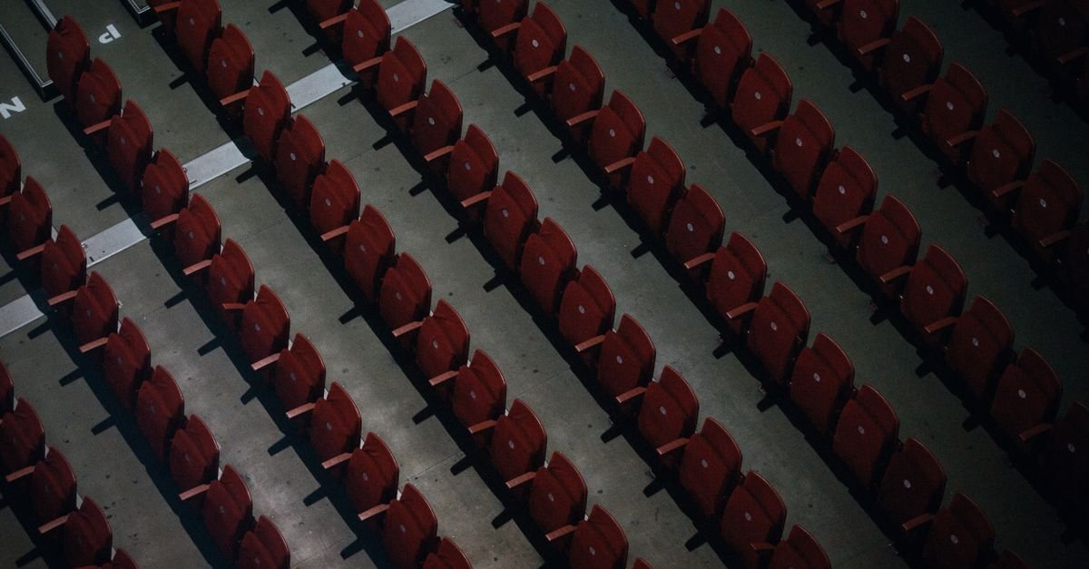 Overhead shot of aligned empty red stadium seats in rows.