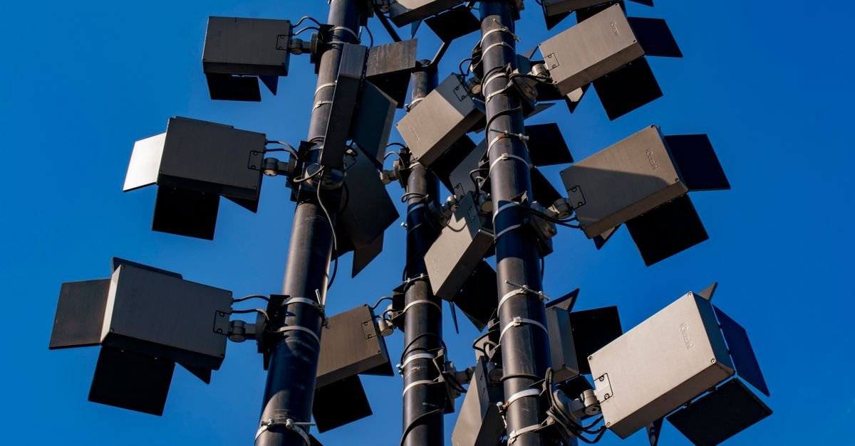 Low angle view of modern outdoor stadium floodlights against a clear blue sky.
