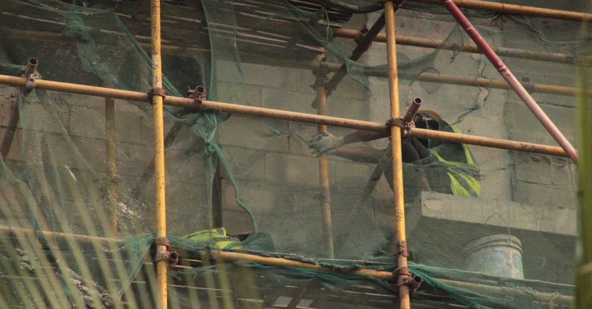 Workers on a building site, secured with scaffolding and safety netting.
