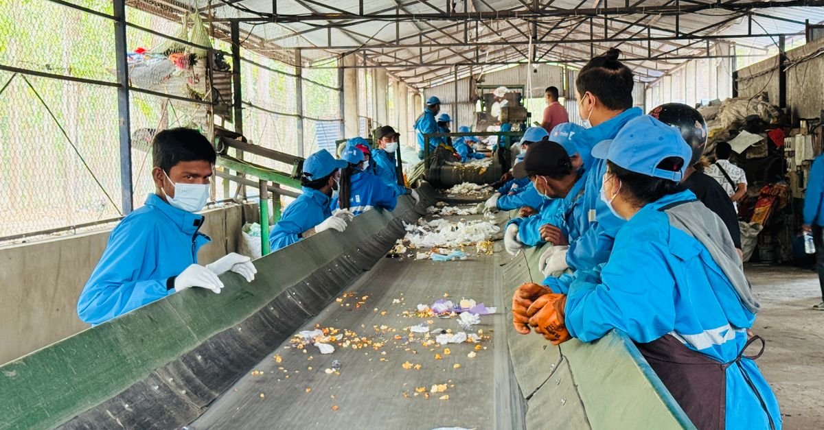 Workers in blue uniforms sorting waste at a recycling facility in Butwal, Nepal.
