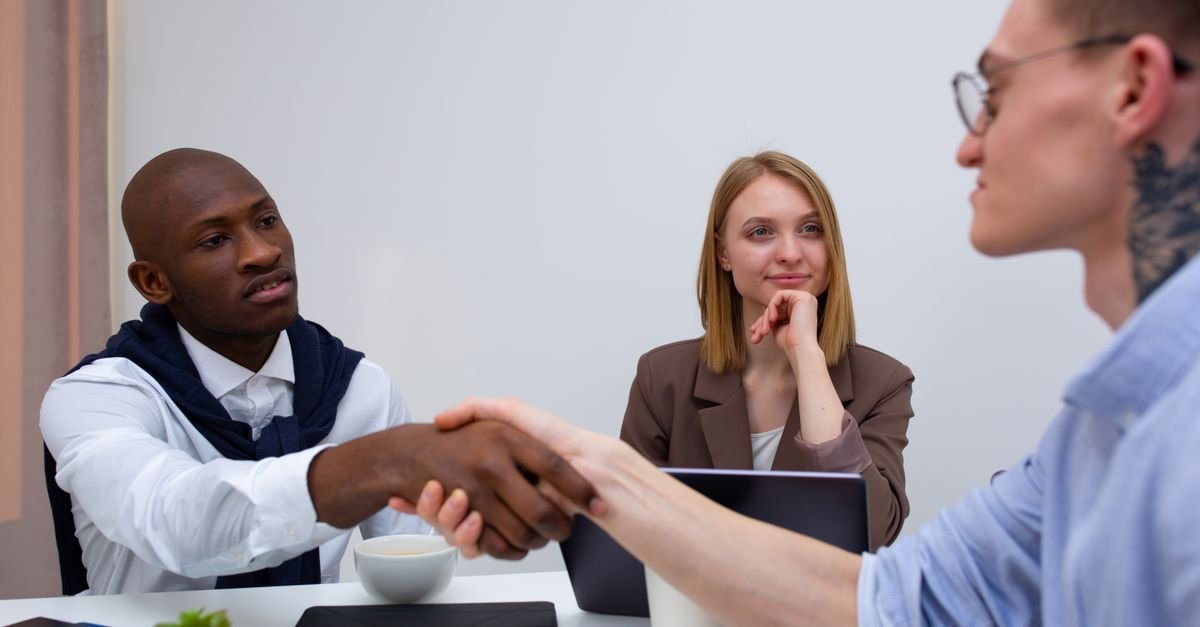 Colleagues in a business meeting shaking hands, showcasing cooperation and diversity.