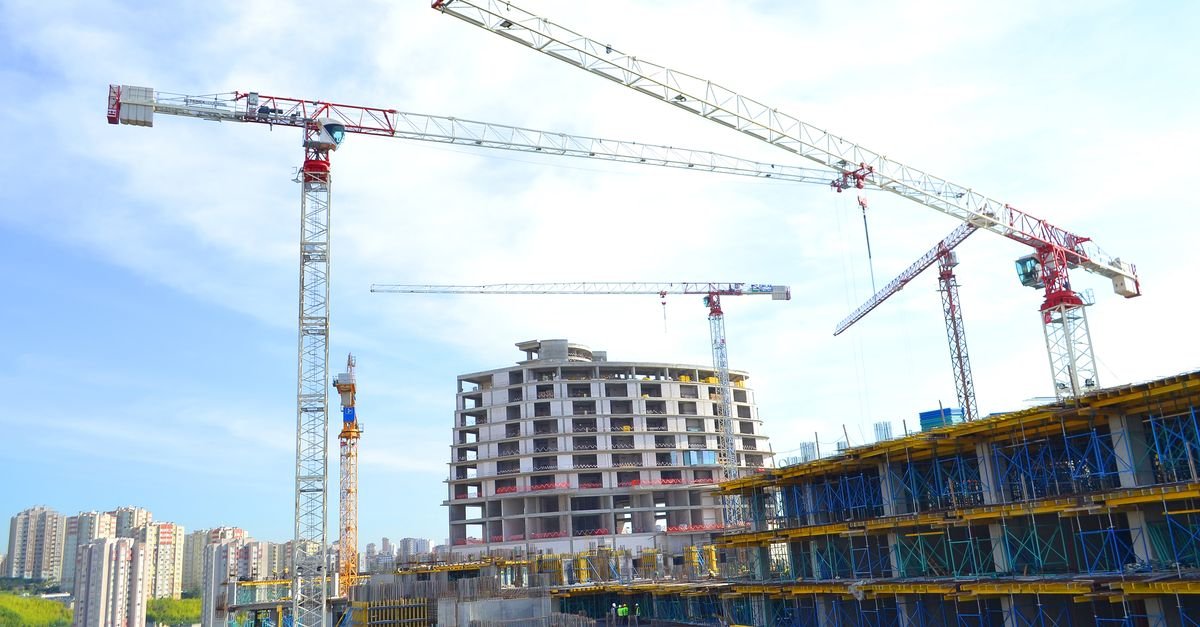 Urban construction site featuring multiple tower cranes against a city skyline.