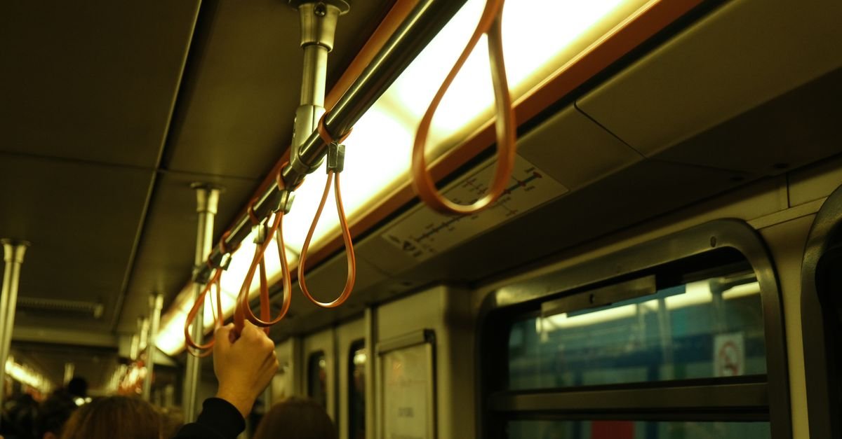 Interior view of a subway train with passengers holding on to handrails, providing a glimpse into urban public transport.