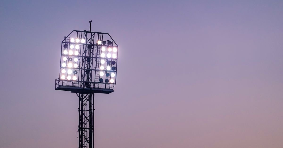 Bright stadium floodlights illuminating the sky during twilight.