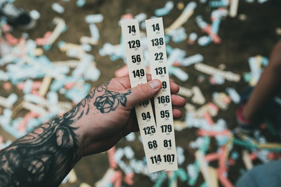 Mão tatuada segurando bilhetes de rifa com números visíveis