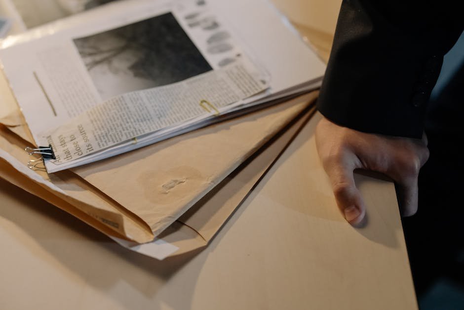 Mão sobre envelopes e documentos investigativos em mesa