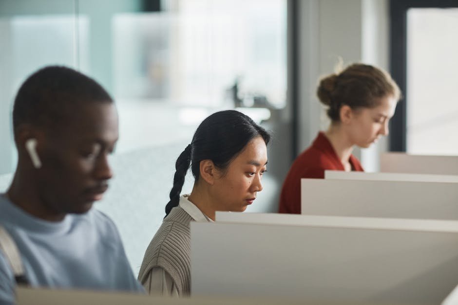 Funcionários trabalhando em cubículos de escritório com computadores