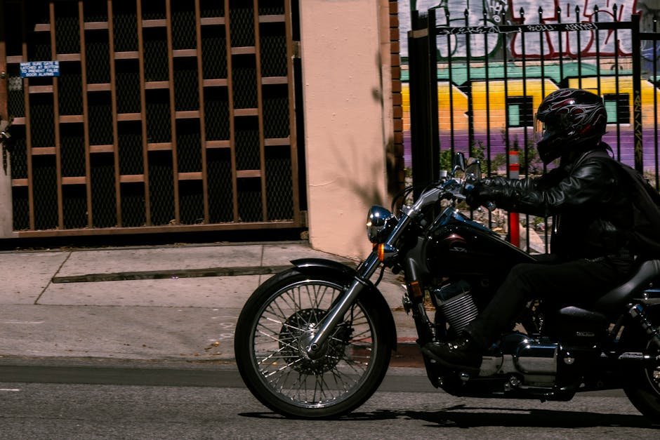 Pessoa pilotando motocicleta em rua urbana com mural ao fundo