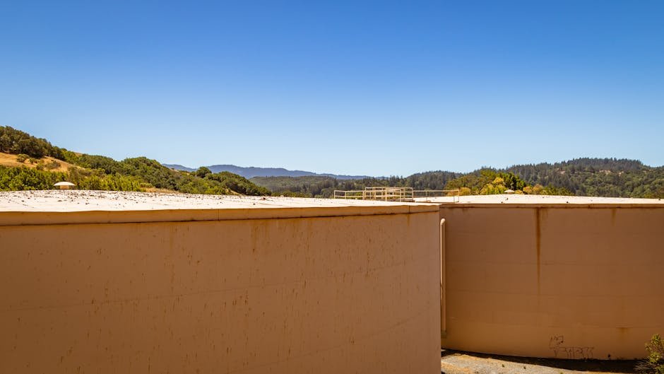 Tanques industriais de água com colinas verdes ao fundo