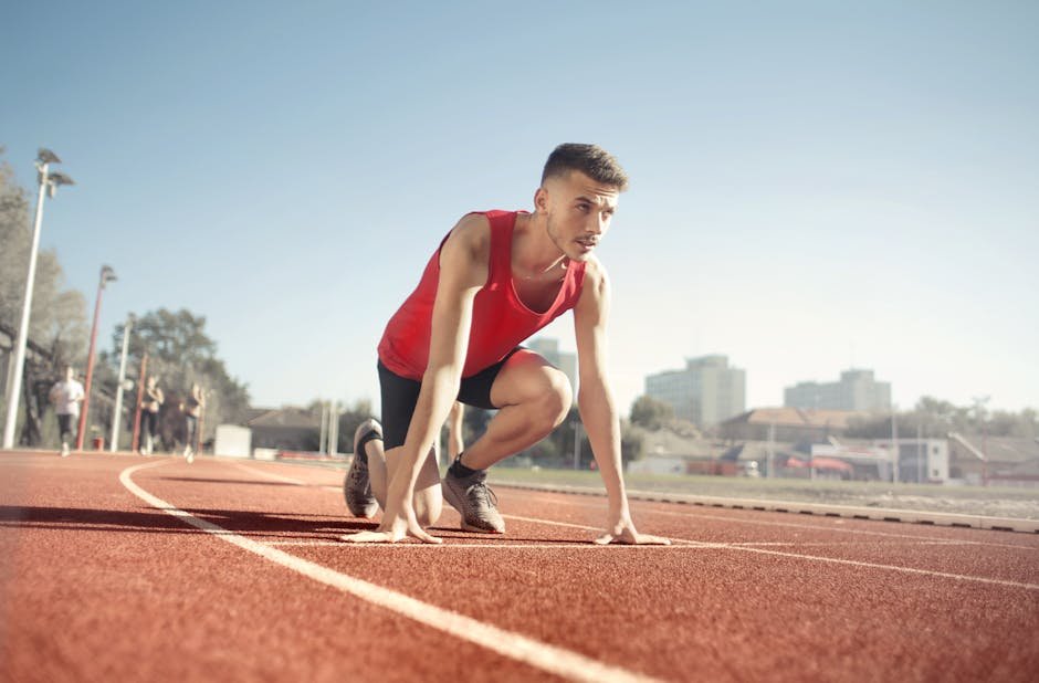 Atleta agachado na posição de partida em pista de atletismo