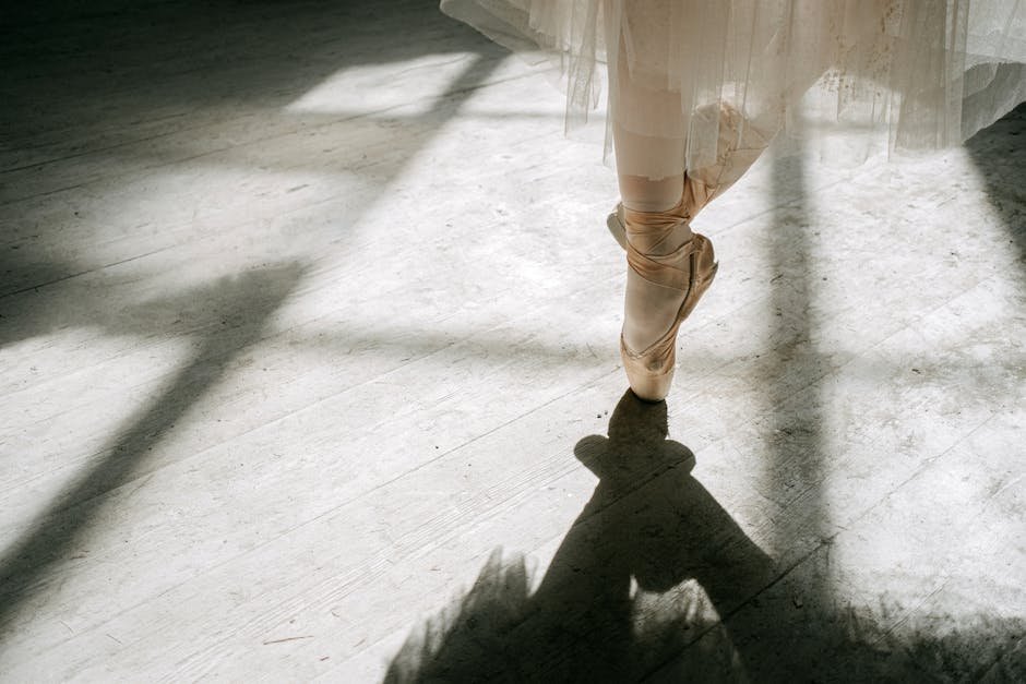 Pés de bailarina em sapatilha de ponta sobre piso de madeira